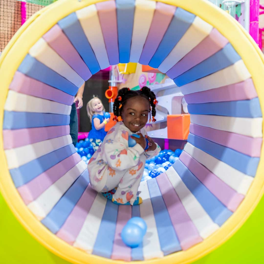 girl crawling through tunnel in indoor playground